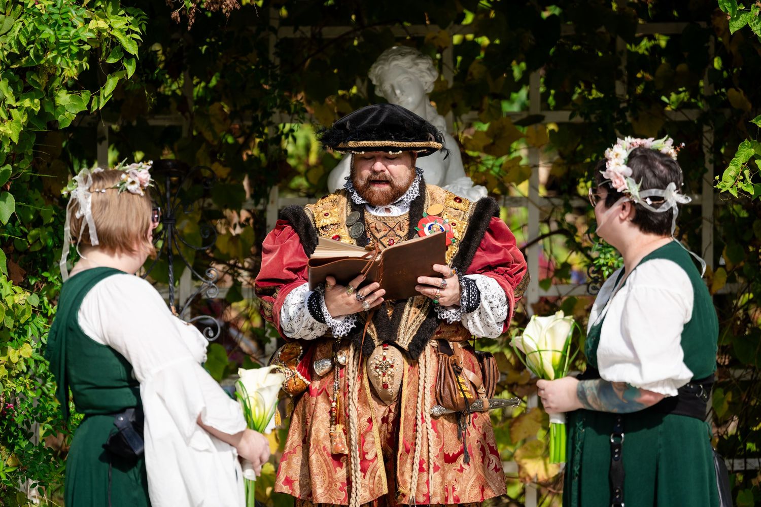 A group of people in Renaissance period costumes performing outdoors in a garden setting.
