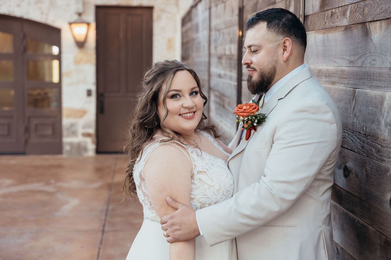 A couple share an intimate moment against a brick wall during their wedding photoshoot.