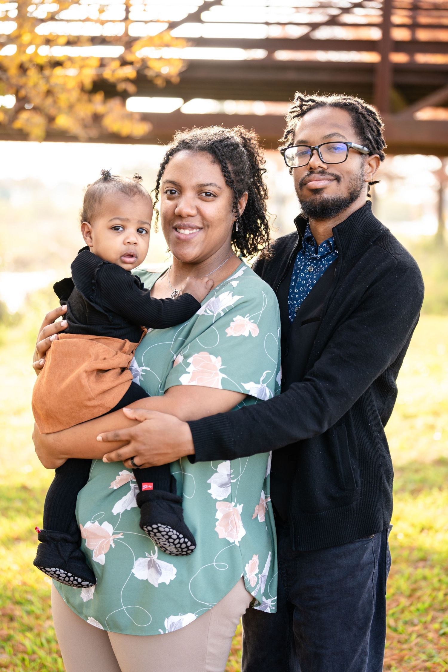 A beautiful family portrait taken outdoors with autumn colors in the background.