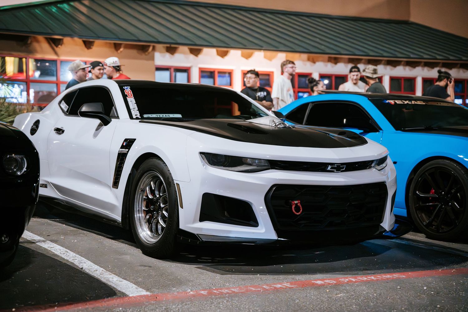 Modified white Chevrolet Camaro ZL1 parked outside restaurant.
