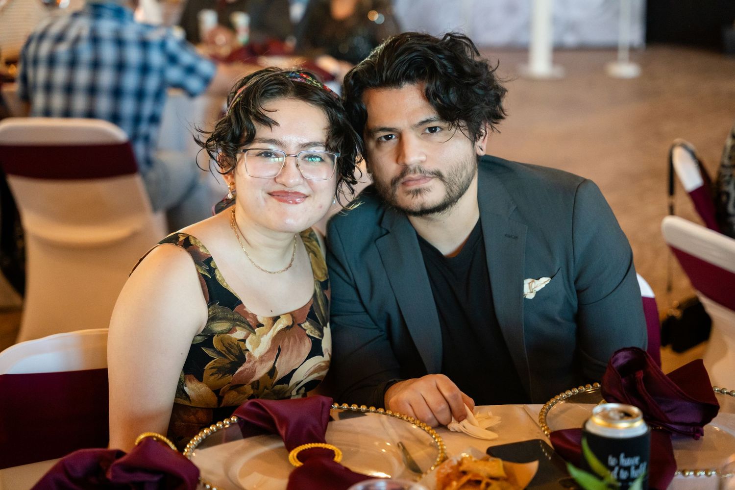Wedding guests seated at reception dinner tables with burgundy decor.