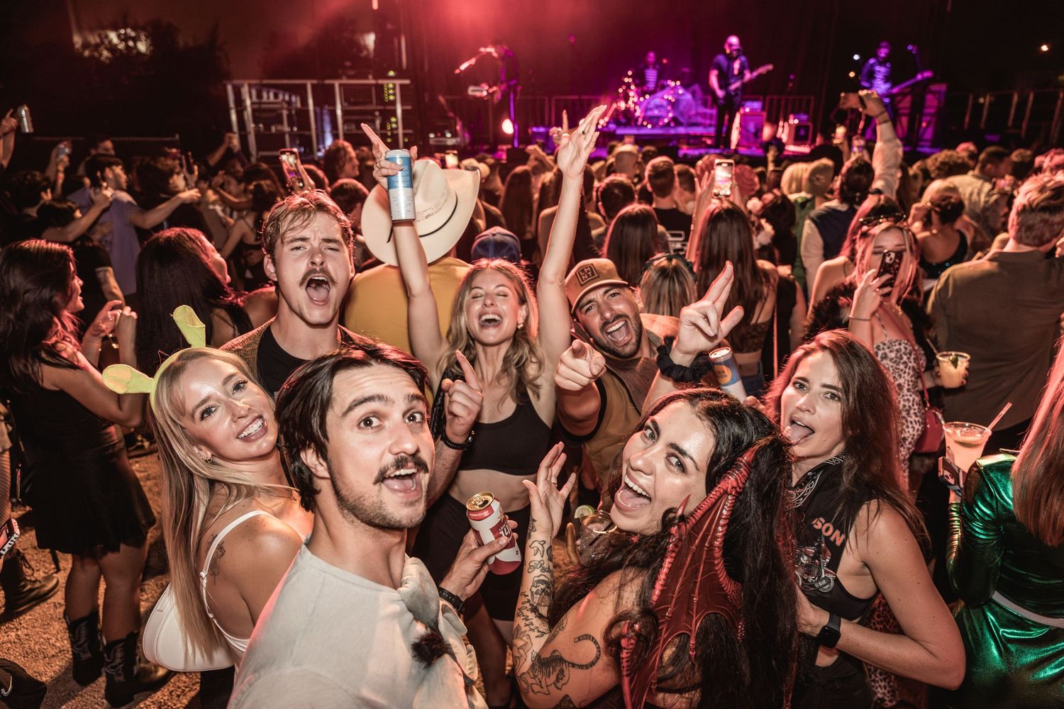 Excited crowd of festival attendees dancing and celebrating at a music event.