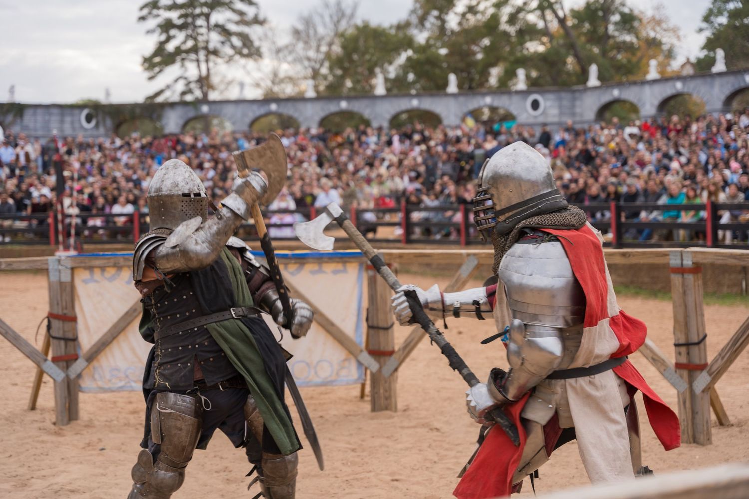 Knights in full armor clash swords during a renaissance fair combat demonstration.
