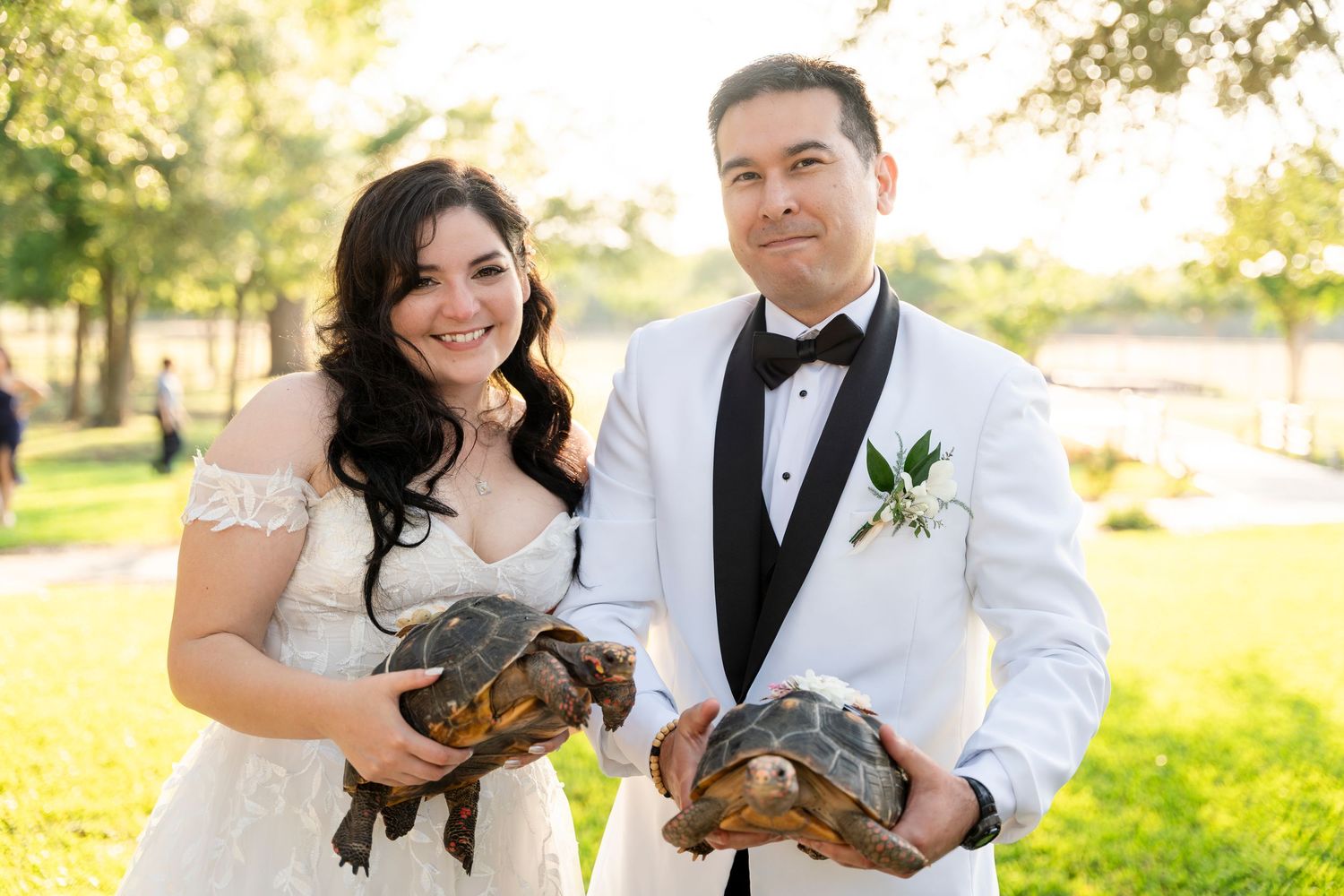 A joyful couple shares tender moments in an outdoor park setting at golden hour with a warm glowing sunset backdrop.