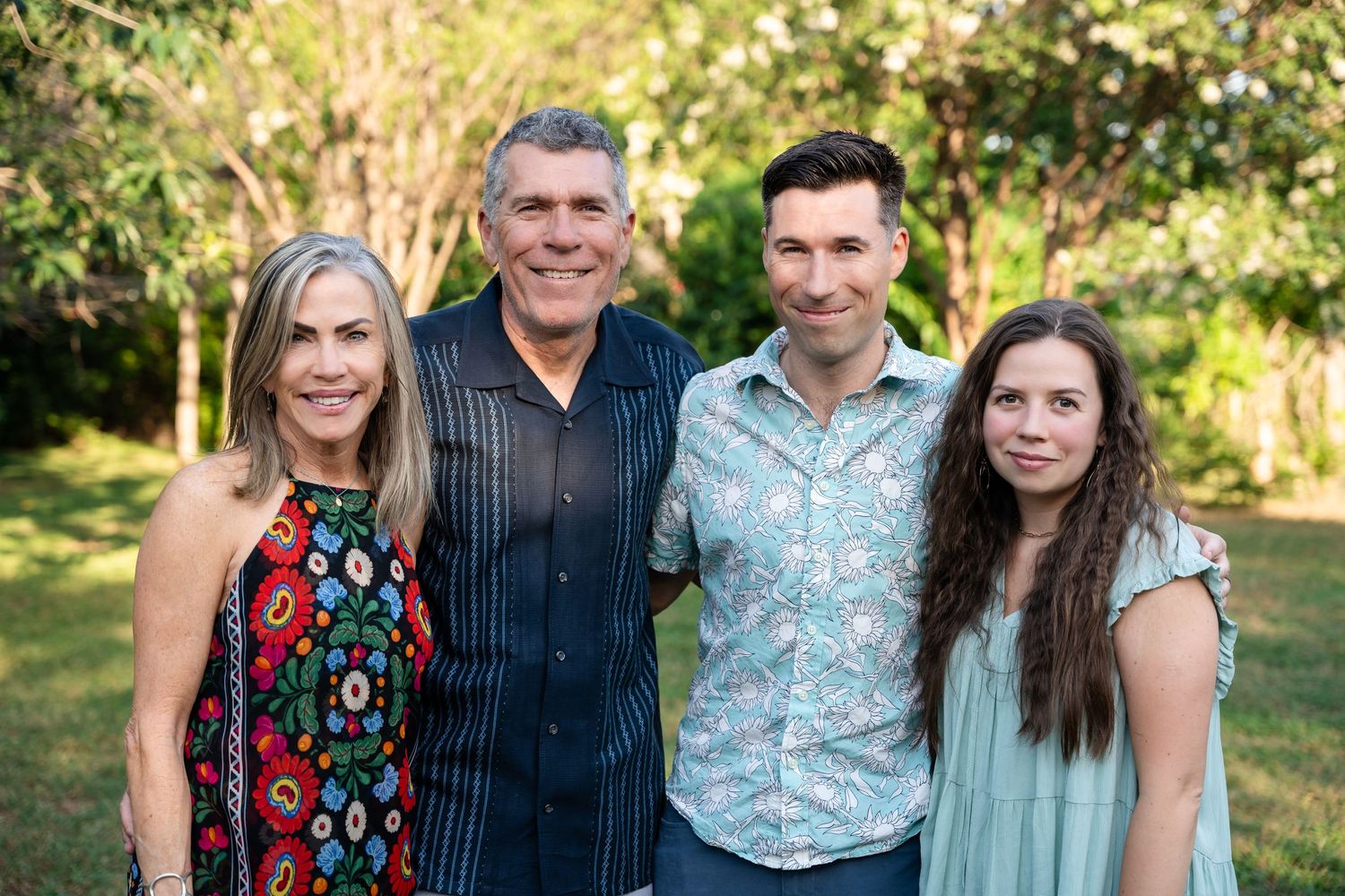 Small group poses for casual outdoor family photo in garden setting.