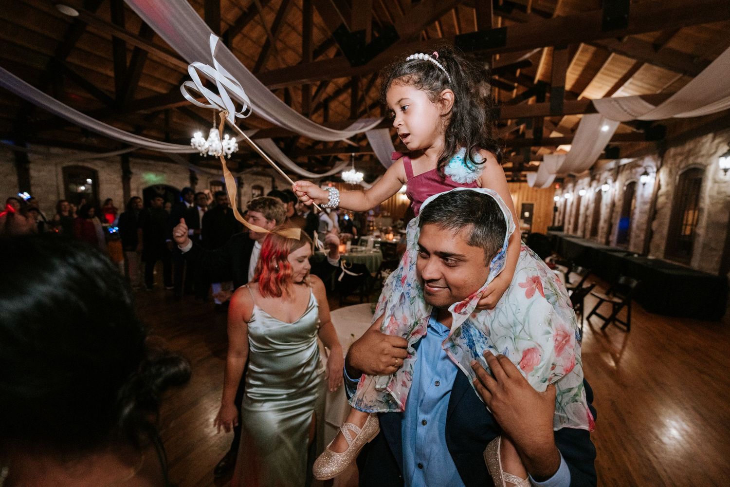 Party guests dancing and celebrating with joy at an indoor reception venue.