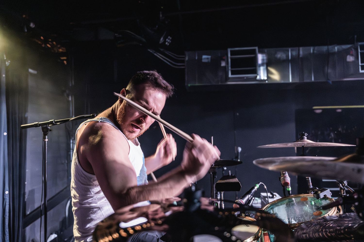Drummer plays with intensity during a high-energy performance on stage.