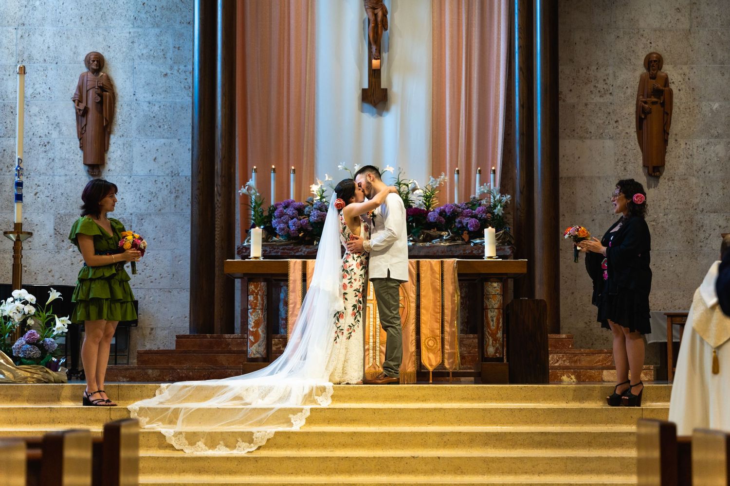 A couple shares their first kiss during their wedding ceremony in a grand cathedral setting.