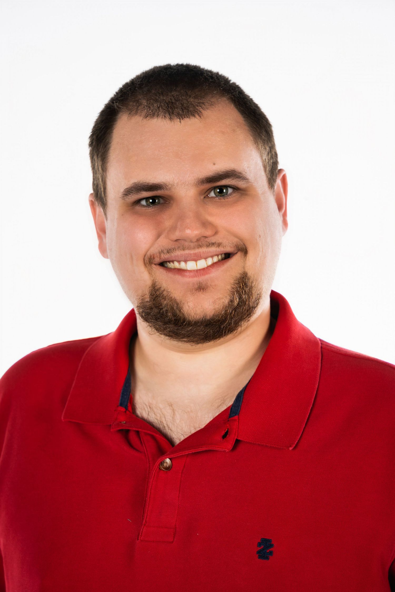 Professional headshot of someone in a red polo shirt smiling at the camera against a white background.