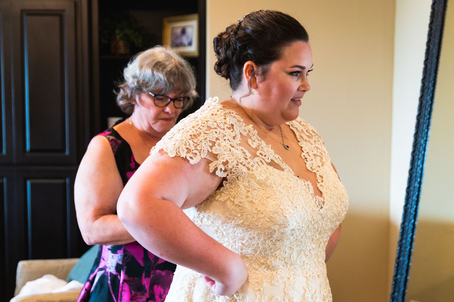 Wedding dress fitting session showing intricate lace details on cream-colored gown.