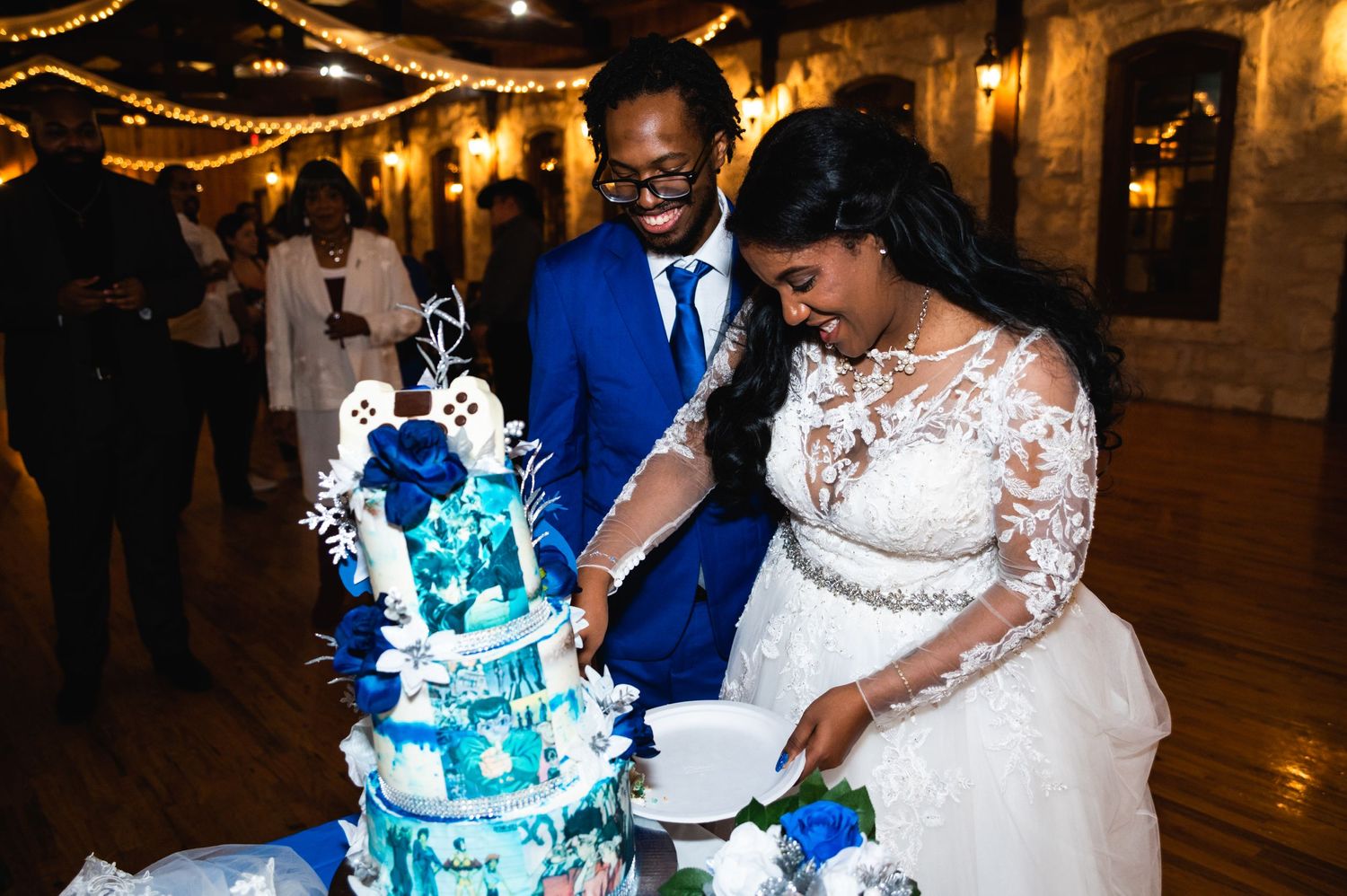 Newlyweds slice into their stunning blue and white multi-tier wedding cake together.