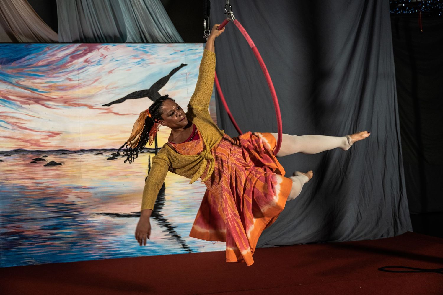 Two dancers in Native American inspired costumes performing against a sunset backdrop.