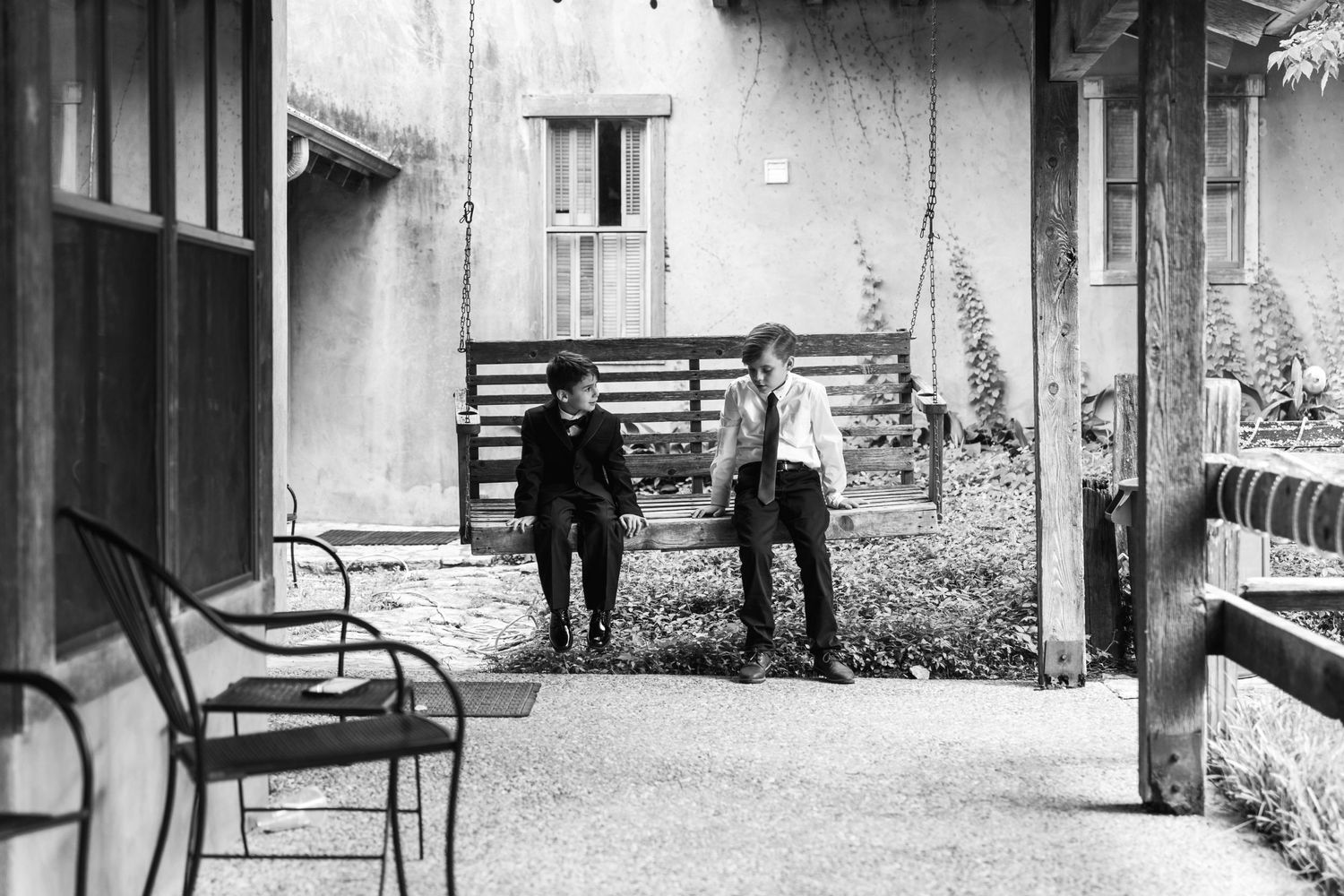 A vintage black and white photo shows two people standing in conversation outside a building.