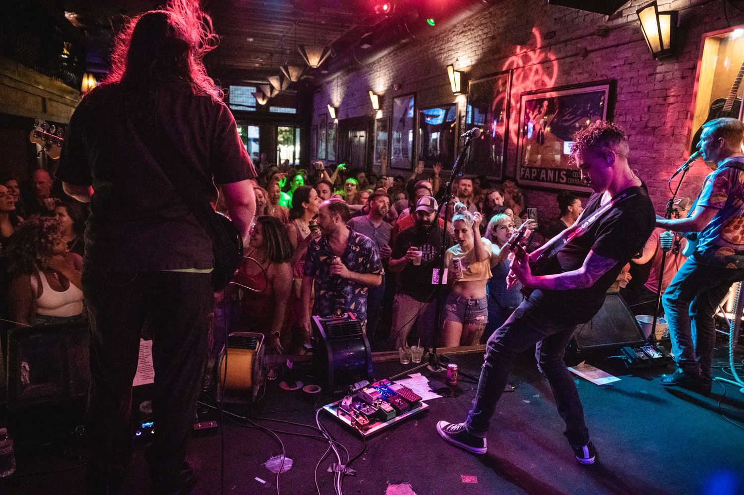 Band members performing on stage with dramatic purple and red lighting effects.