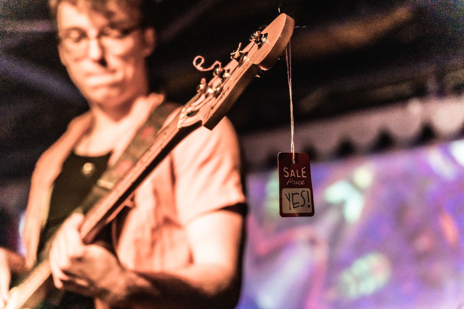 Musician performing on stage with guitar in dramatic lighting.