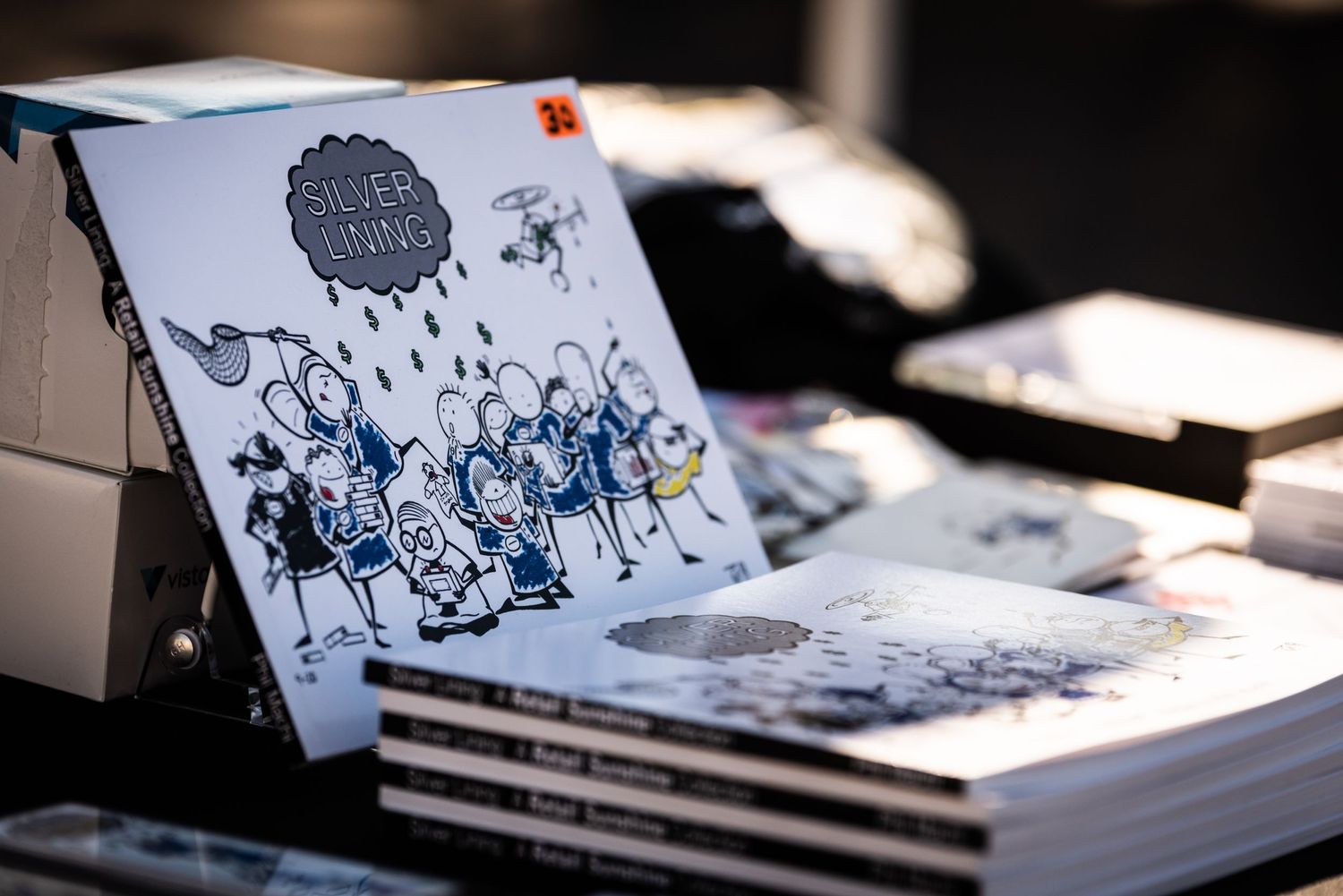 Stack of printed books or albums with artistic black and white illustrated cover design.