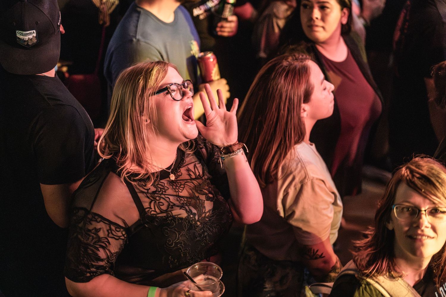 Concert attendees enjoying live music with enthusiastic expressions and gestures in warm lighting.