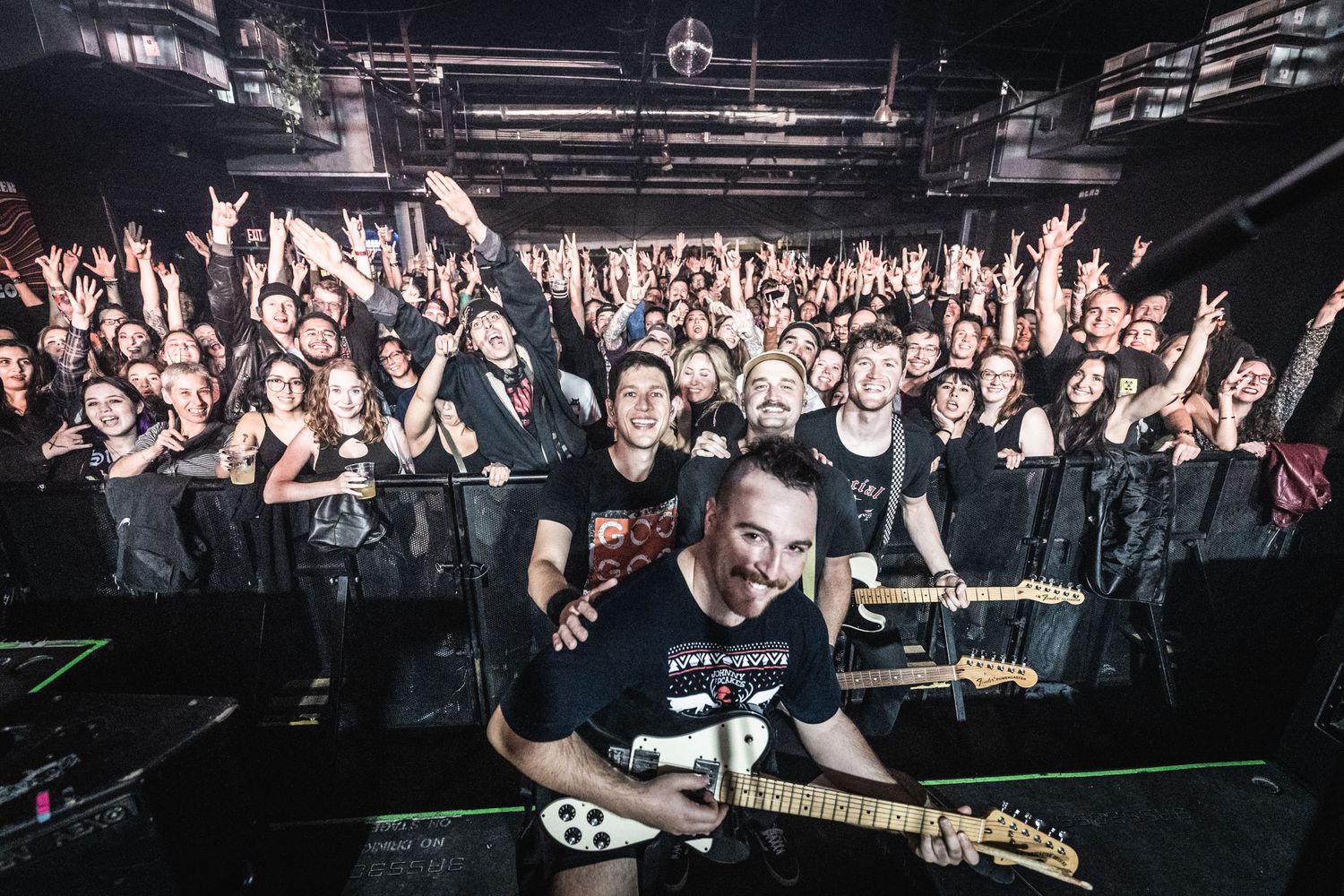 Concert photo showing performers on stage with energetic crowd in the background.