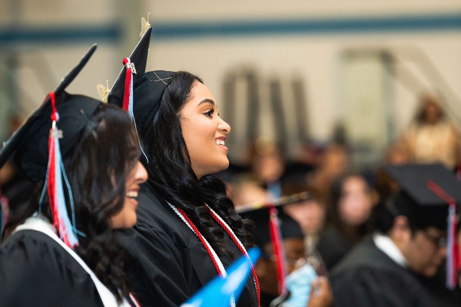 Graduates in caps and gowns smiling during a graduation ceremony.