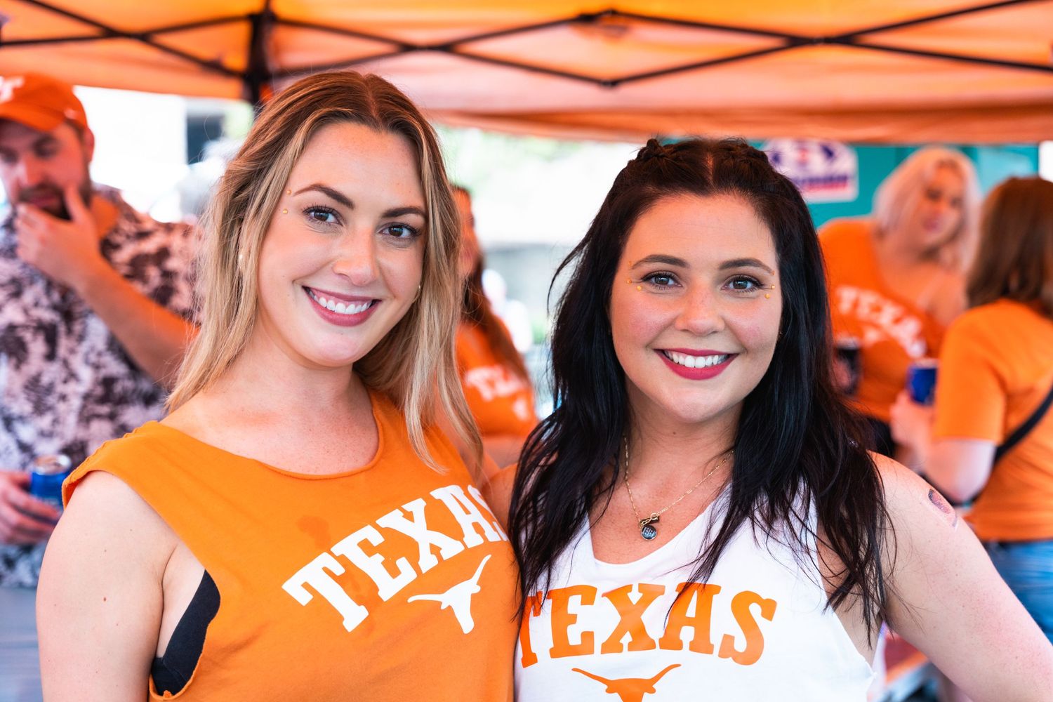 People wearing orange Texas shirts smiling at an outdoor gathering.