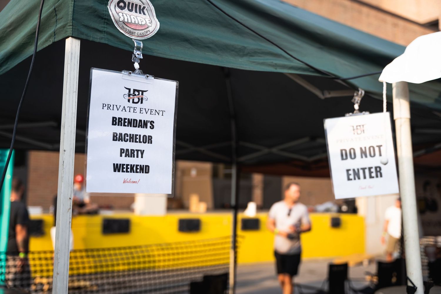 Event signage showing 'Do Not Enter' and bachelor party weekend details under tent.