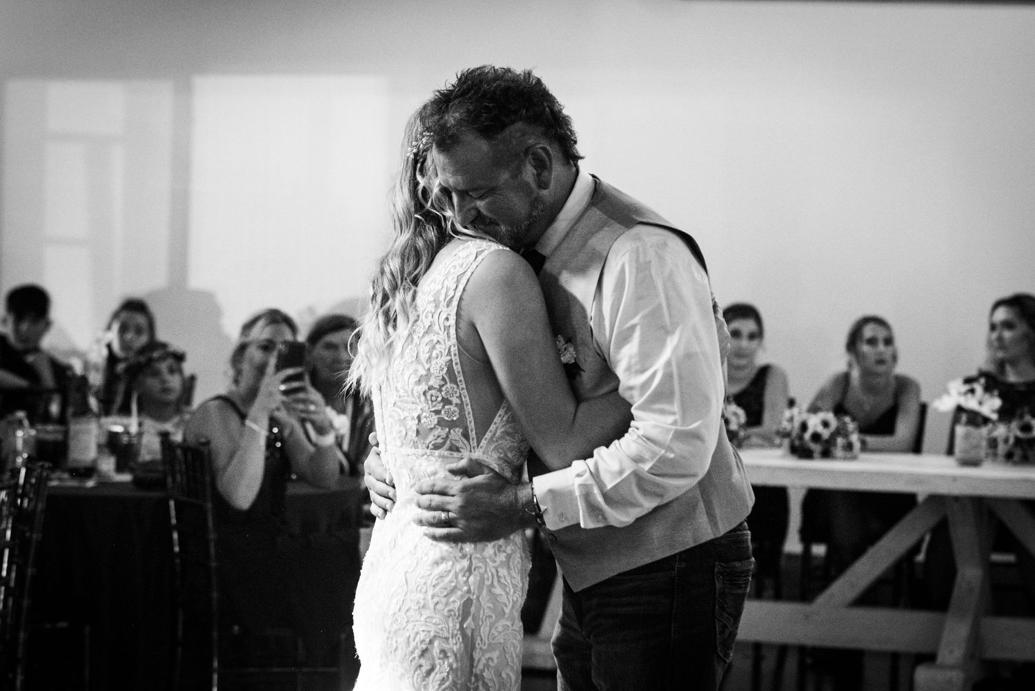 Intimate black and white moment during wedding dance in rustic reception venue.