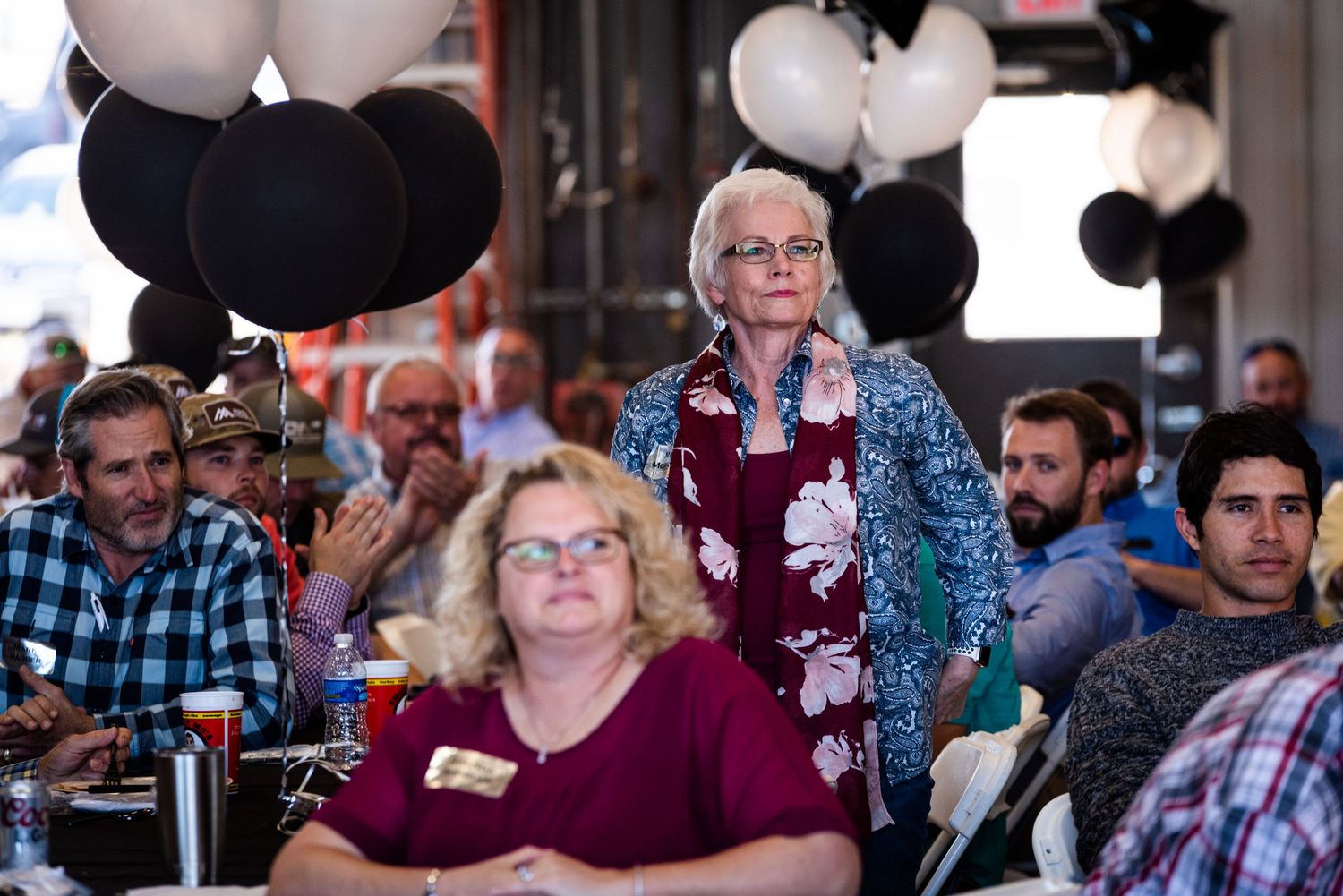 Audience members attend an event with black balloons decorating the venue.