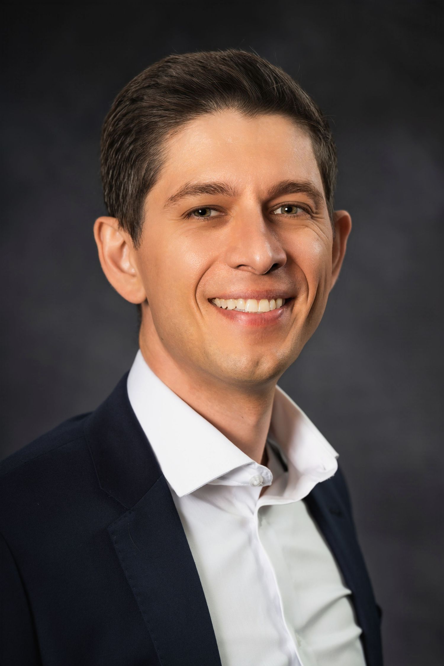 Studio headshot of a business professional in business casual attire with white shirt.