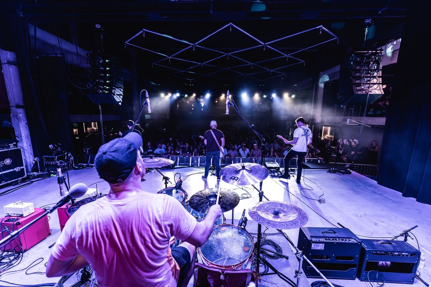 Wide stage shot showing band performing under dramatic purple lighting and stage effects.