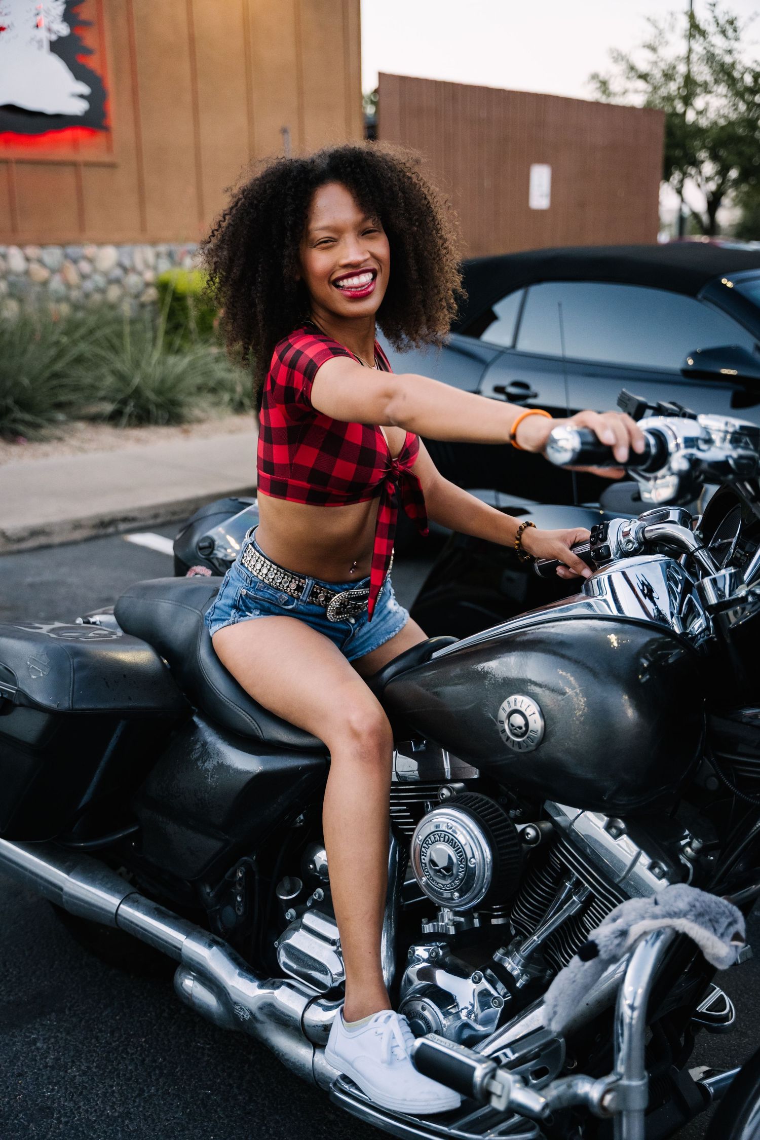 Person riding black Harley Davidson motorcycle at car meet event.