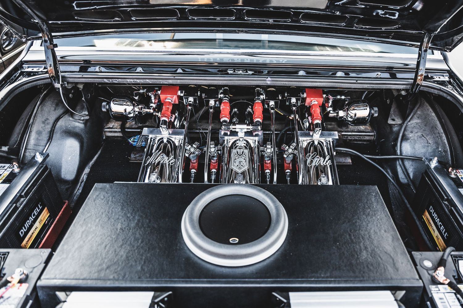Custom car audio system installation with multiple amplifiers in black trunk compartment.