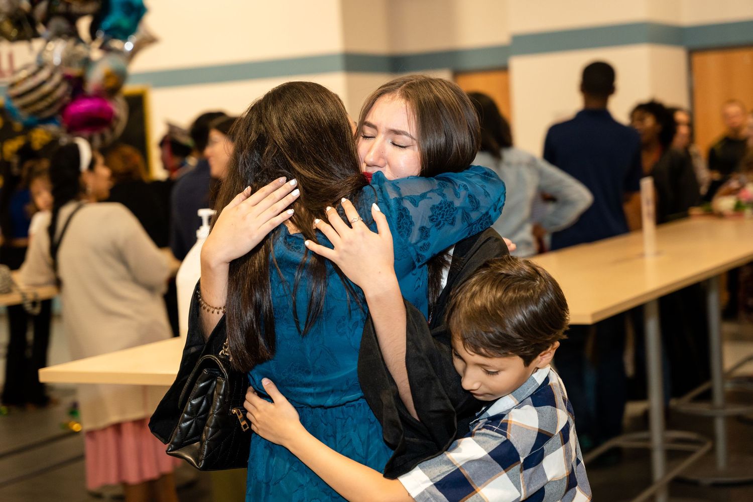Emotional graduation moment as family members share warm embraces.