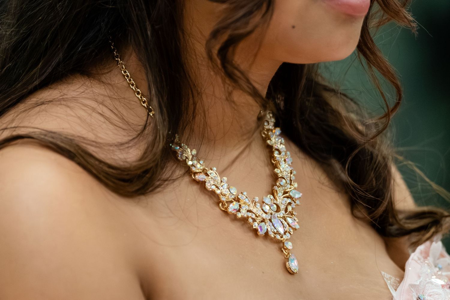 Gold crystal bridal statement necklace with floral design worn by a bride in a white dress.