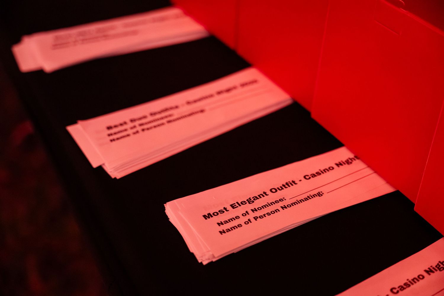 Ballot papers arranged in rows under red lighting at a polling station or election venue.