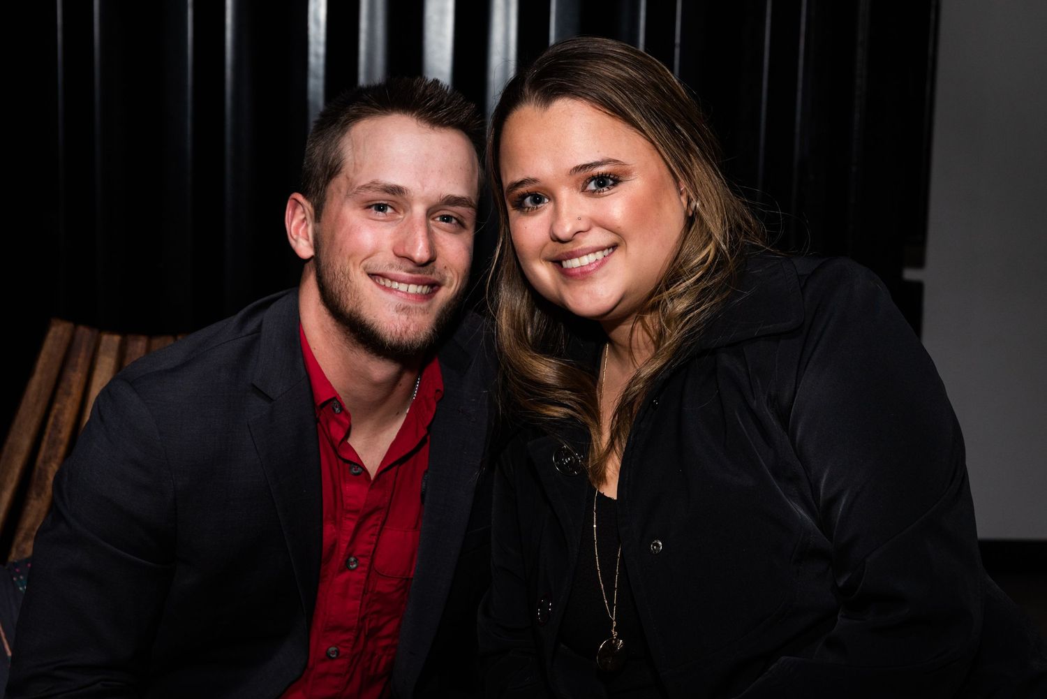 A couple in coordinating red and black outfits smiles together in a series of casual photo booth style snapshots.