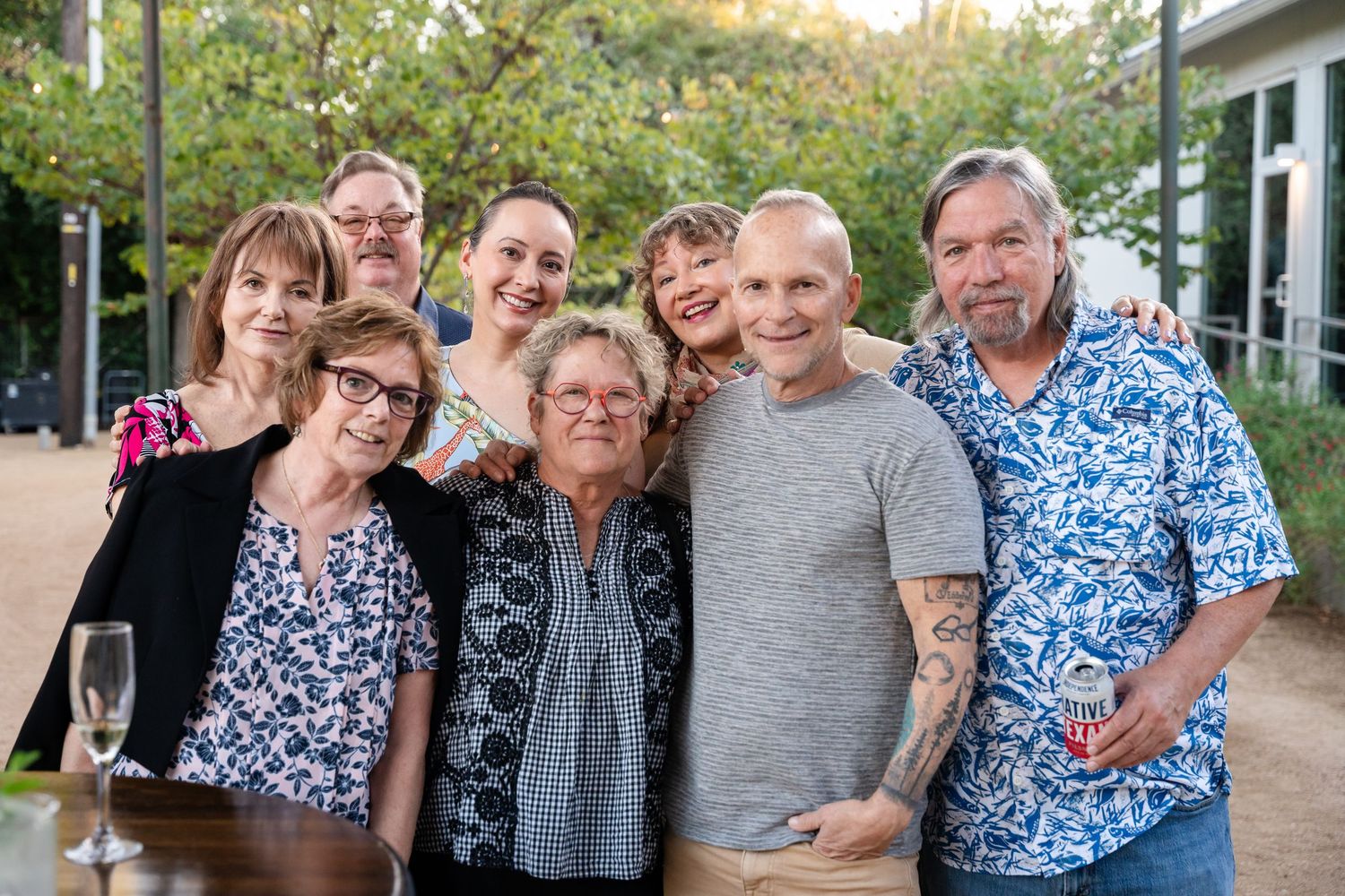 A group of people standing together outdoors on a sunny day, smiling warmly at the camera.