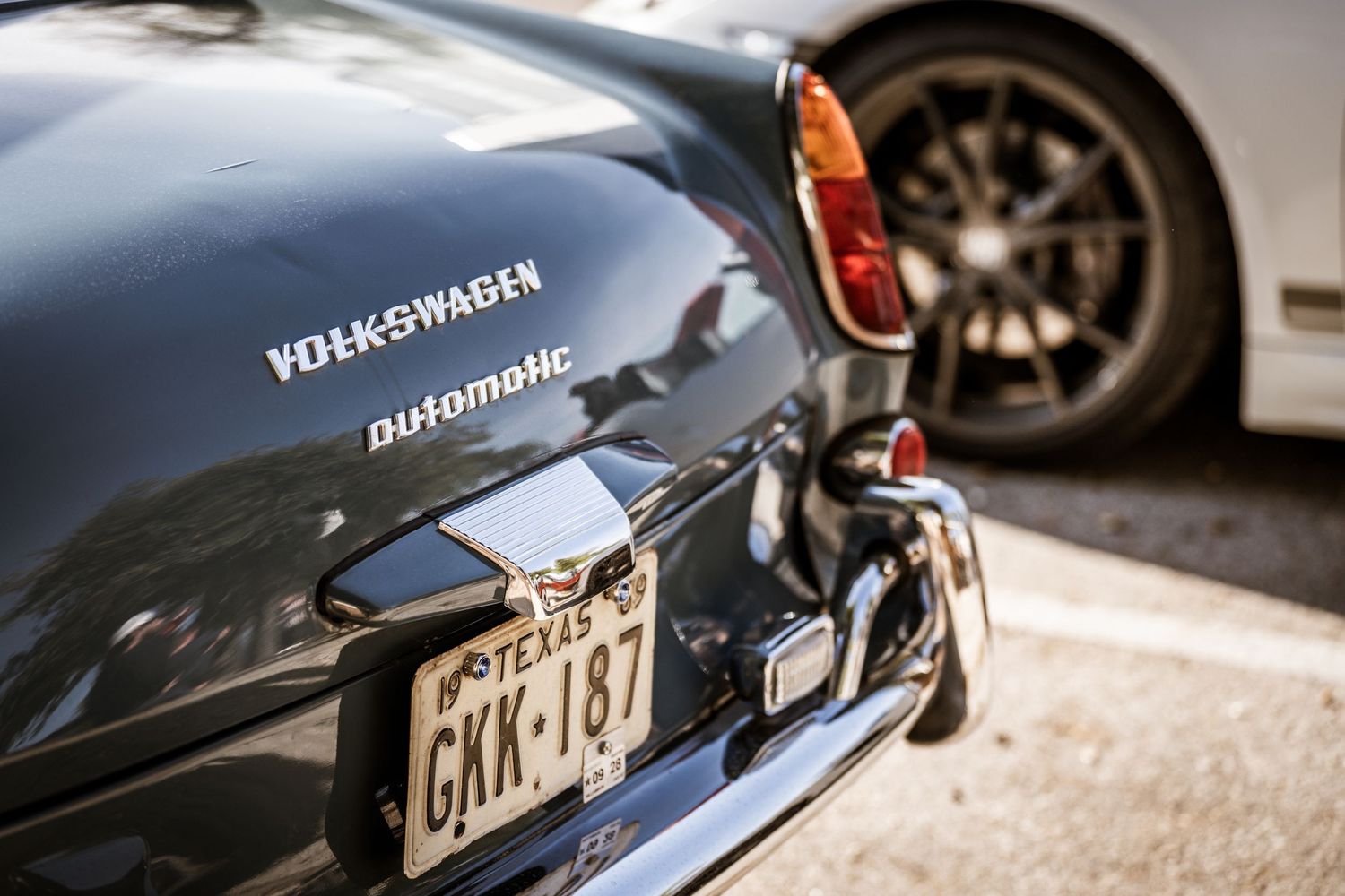 Detail shot of a classic Volkswagen automatic badge and tail lights with vintage Texas license plate.