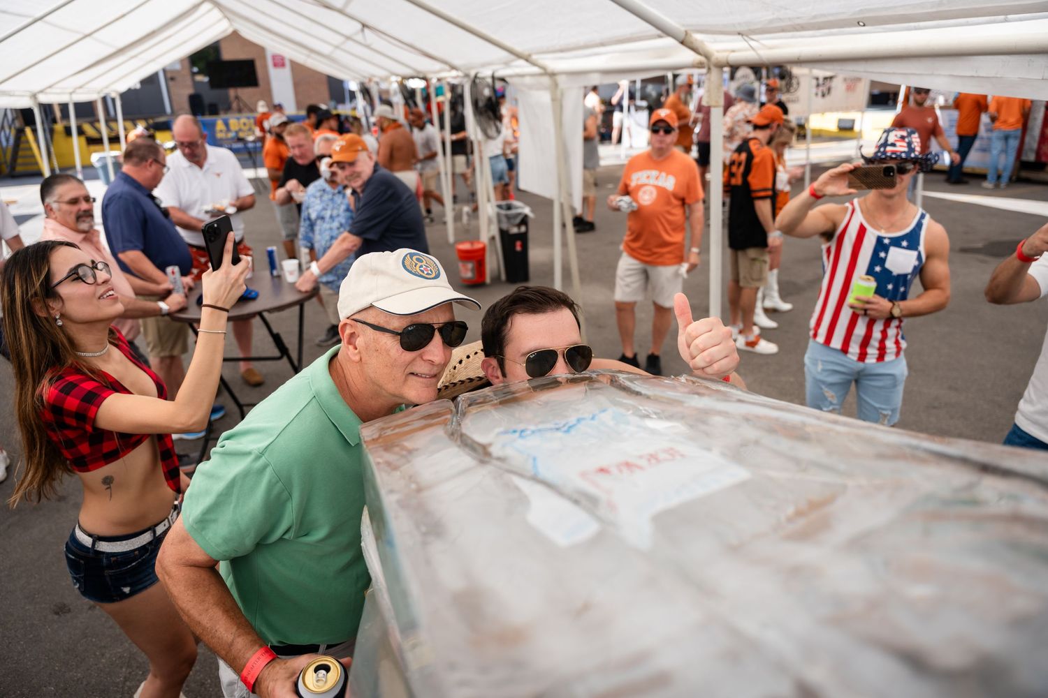 Crowd gathered around ice luge station at outdoor festival event.