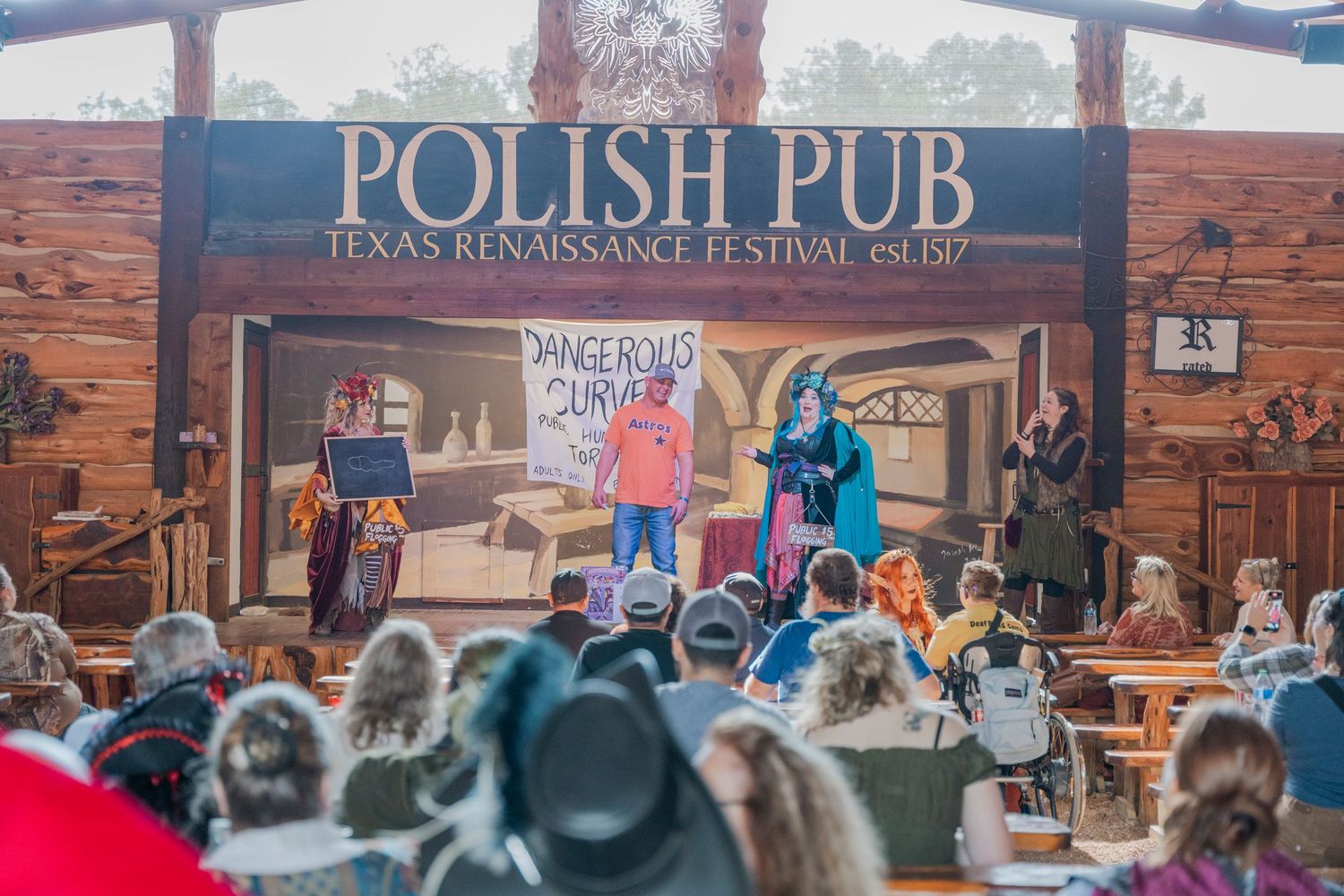 A crowd watches performers on stage at a Polish pub during a renaissance festival.