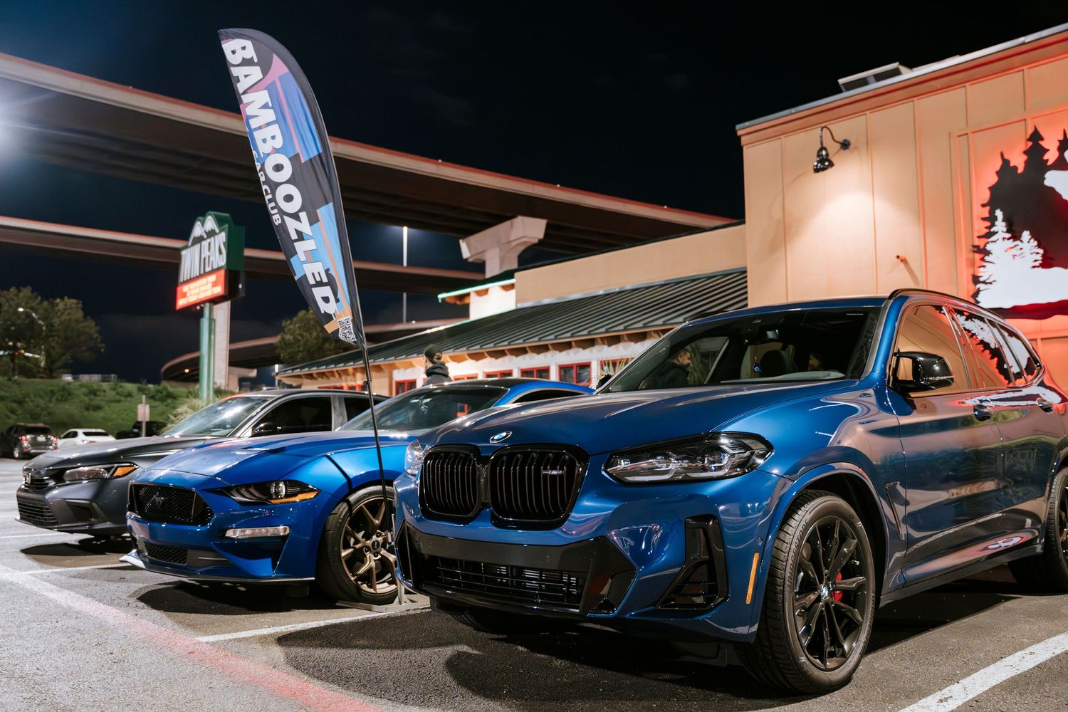 BMW performance vehicles lined up at a nighttime car meet showing sporty styling and blue paint finishes.