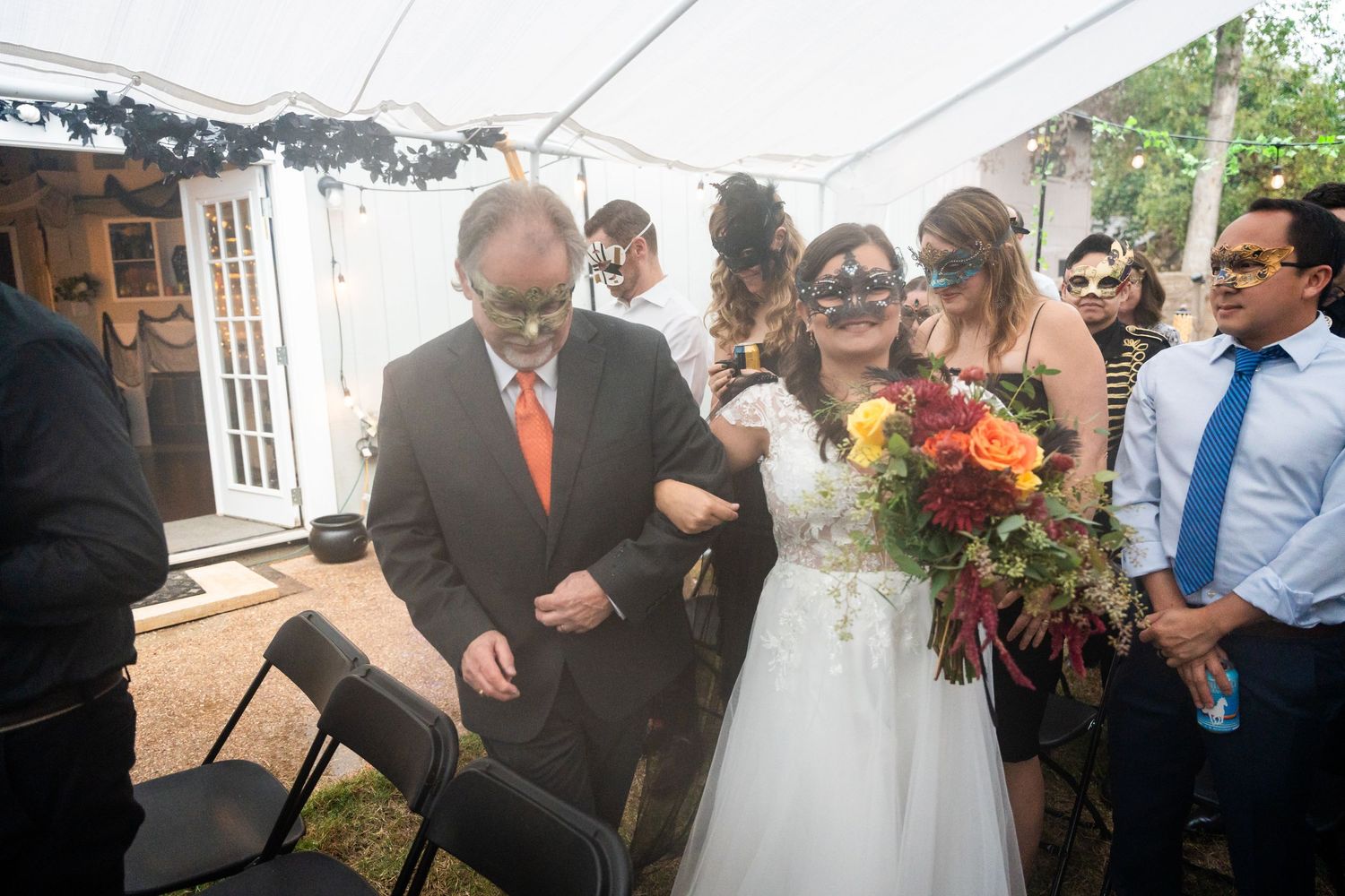Outdoor wedding ceremony under a white tent with guests gathered around.