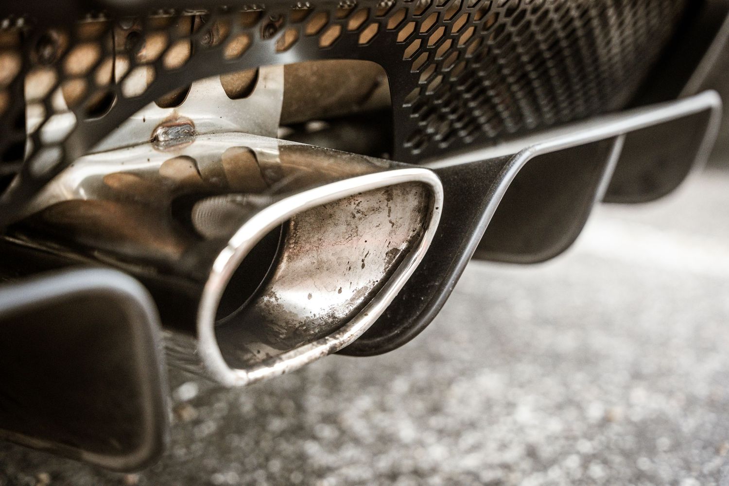 Close-up detail of dual exhaust pipes and muffler on a performance vehicle.