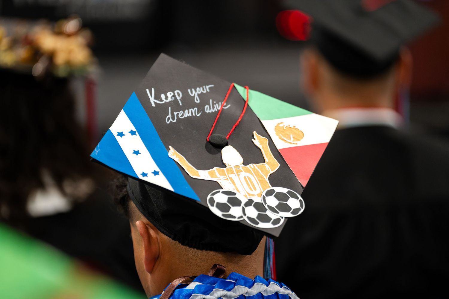 Decorated graduation cap featuring multiple national flags and personal message.