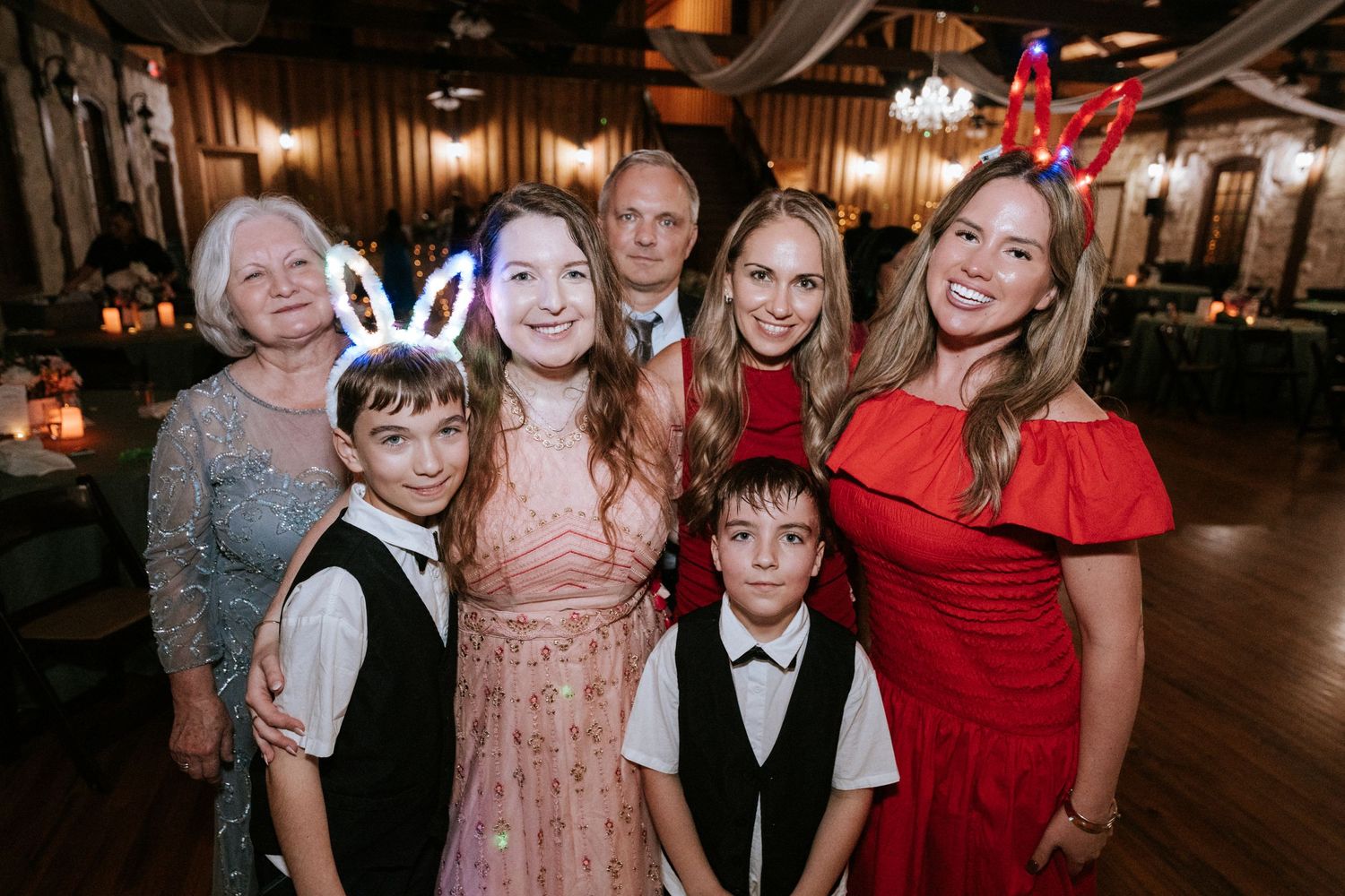 A group dressed in formal attire including pink, red, and black poses together at an event venue.
