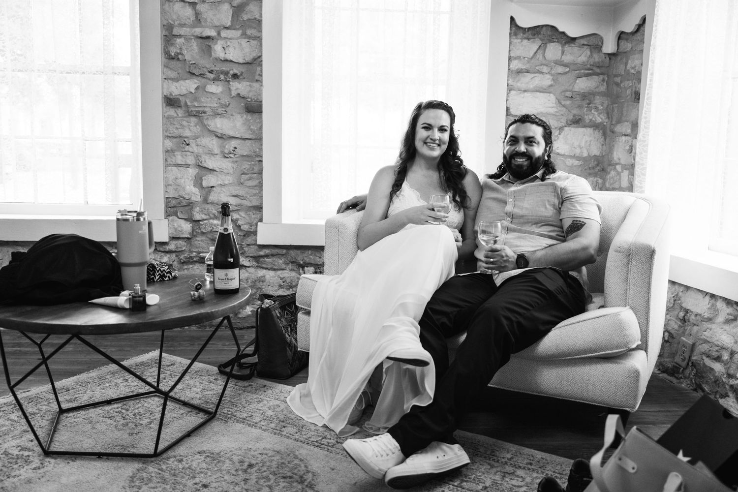 Couple relaxing on couch in casual attire with drinks nearby.