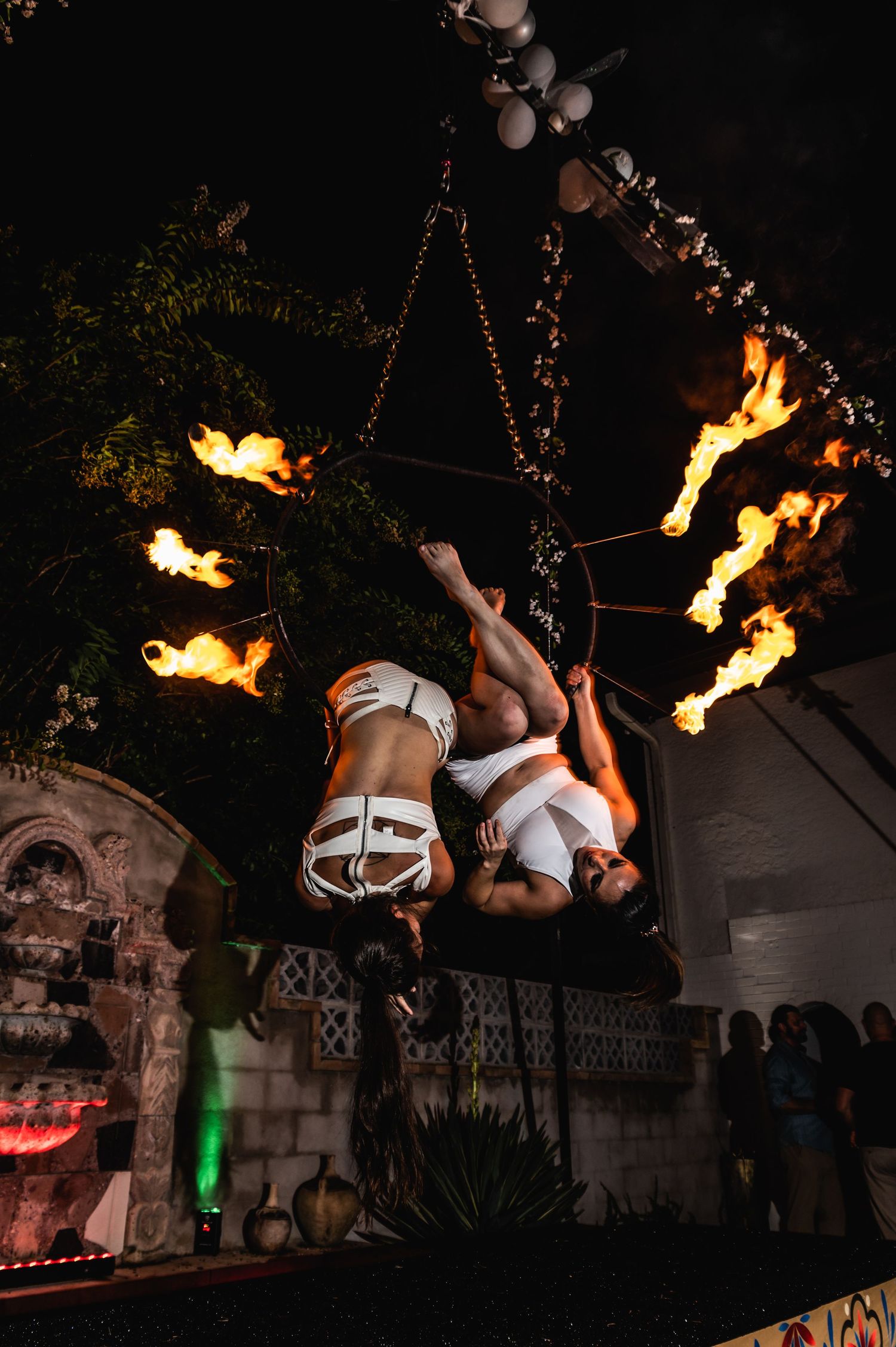 Dramatic fire performance with aerial acrobatics in outdoor nighttime setting.