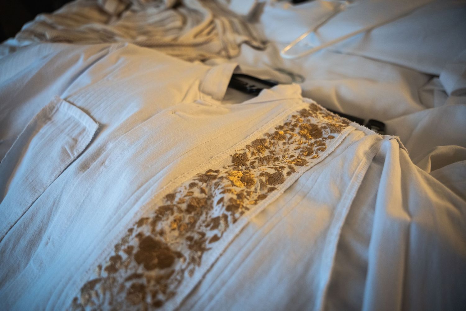 Close-up detail of embroidered white dress fabric with delicate pattern.