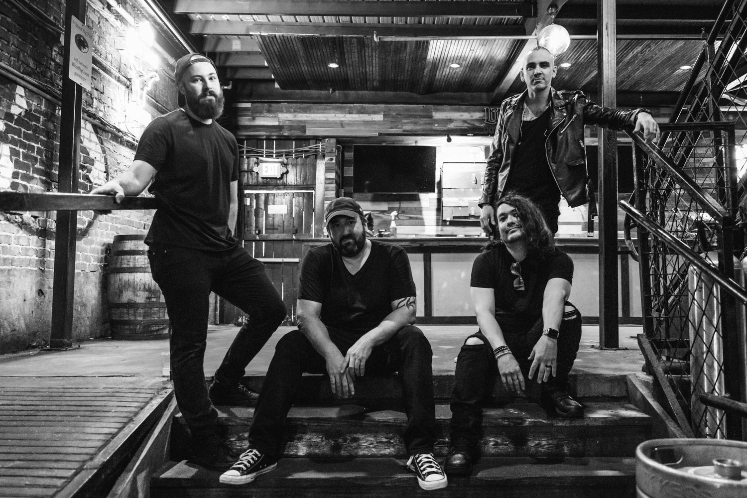 Band members pose for a black and white photo in an industrial basement setting.
