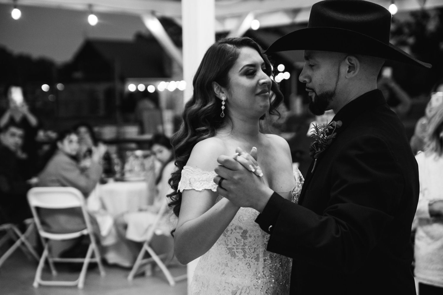 Black and white dance photo of couple in western attire sharing intimate moment at reception.