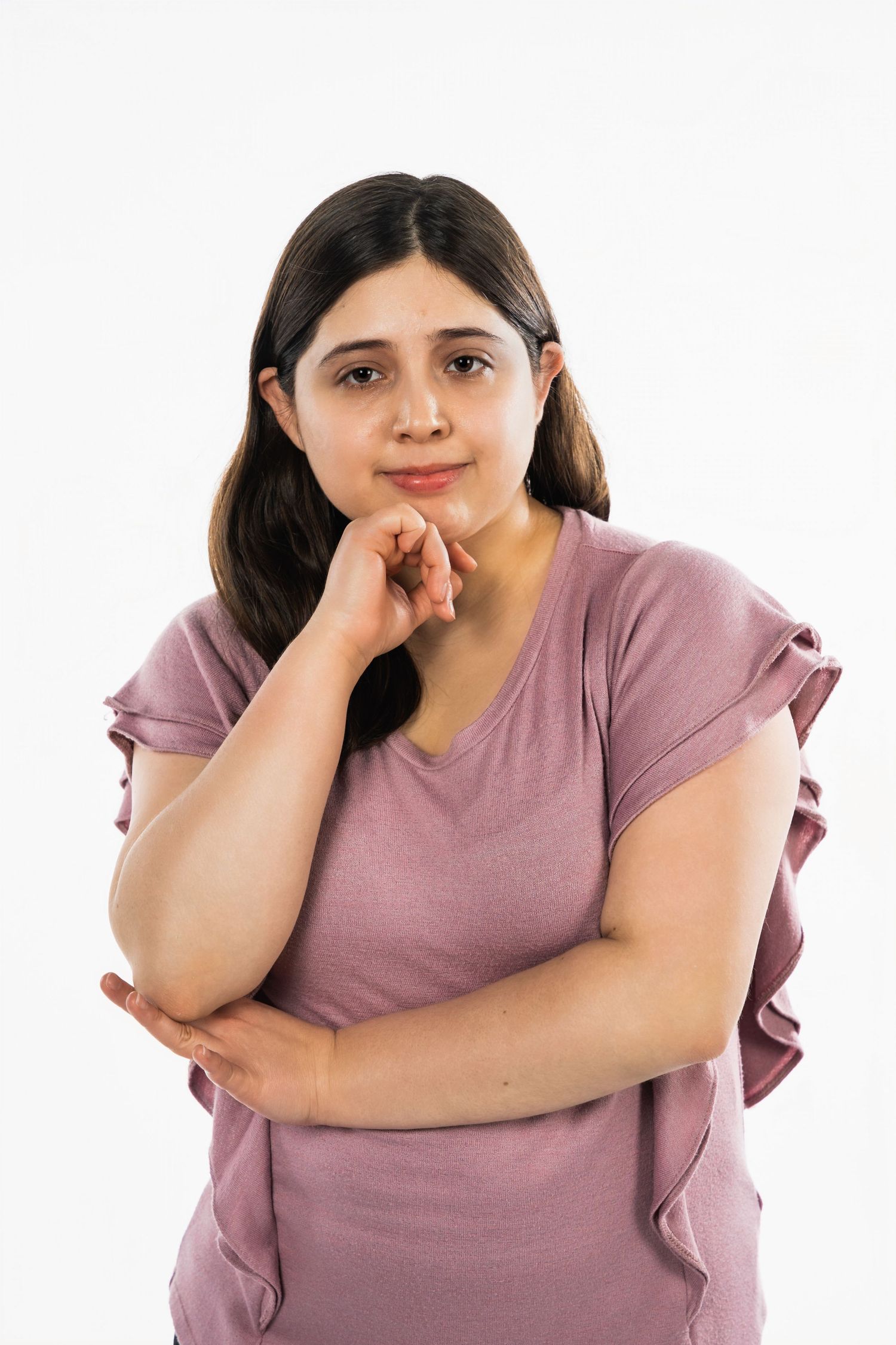 Portrait of someone wearing a dusty pink t-shirt against a white background in a contemplative pose.